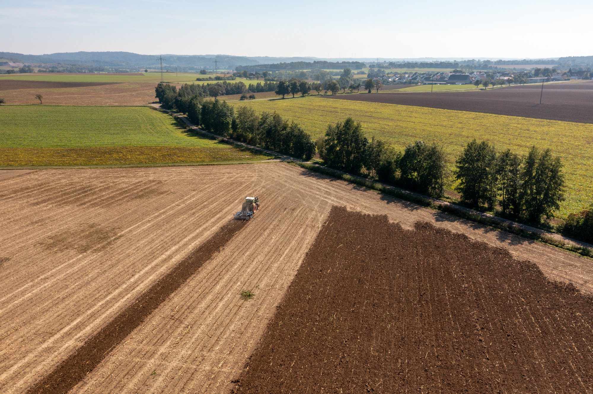 Drone view of a tractor plowing an agricultural field in Germany